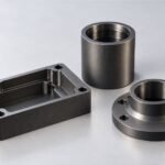 Illustrative dark hardcoat anodized aluminum housing, sleeve and flange on a light gray background